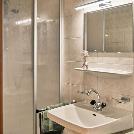 Bad mit Dusche, Waschbecken und Spiegel